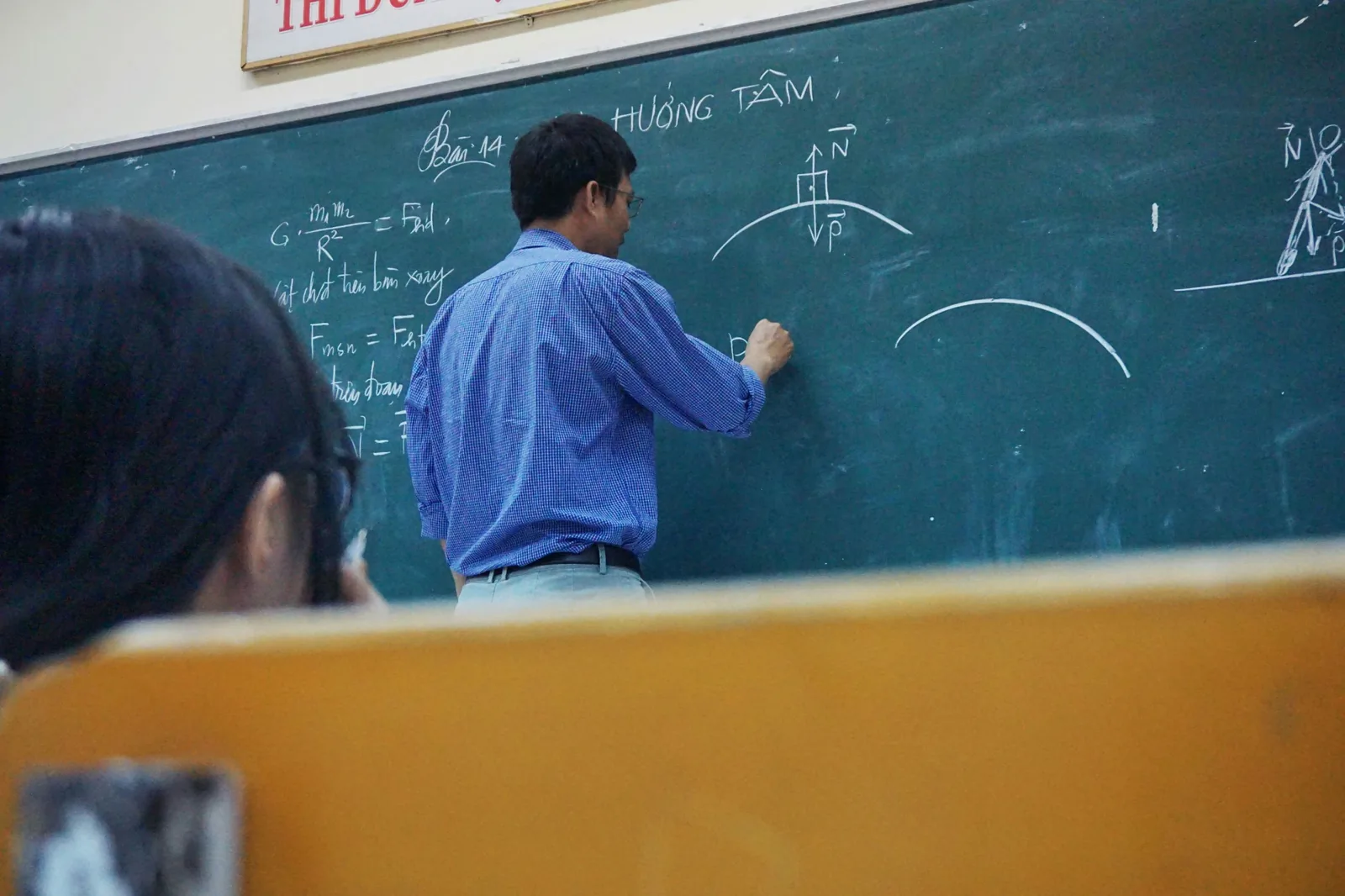 Teacher explaining physics on a classroom board